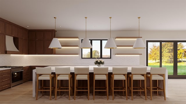 kitchen featuring a breakfast bar area, a center island, stainless steel gas range, custom exhaust hood, and light countertops