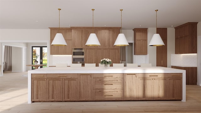 kitchen featuring stainless steel double oven, a spacious island, light countertops, brown cabinetry, and decorative light fixtures