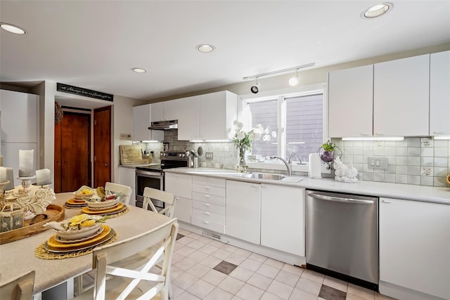 kitchen with sink, light tile patterned floors, appliances with stainless steel finishes, track lighting, and white cabinets