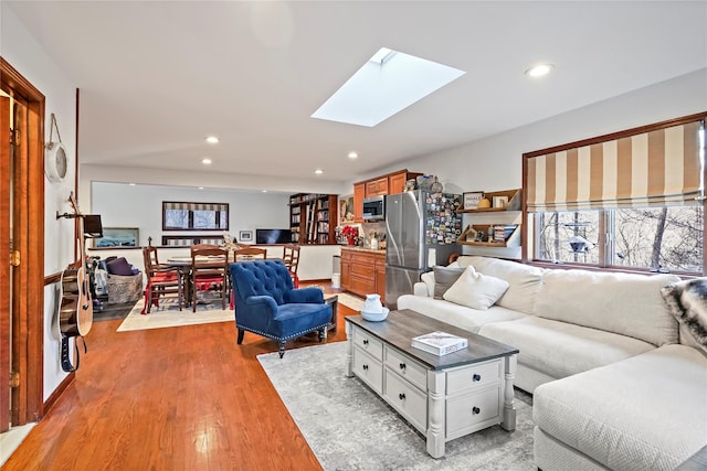 living room featuring a skylight and light hardwood / wood-style floors