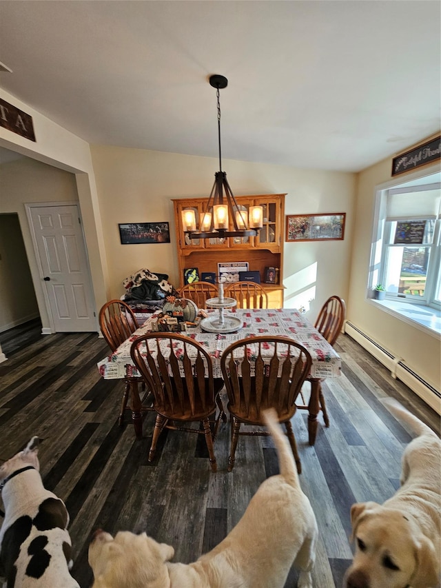 dining space with dark wood-type flooring, a baseboard radiator, and a chandelier