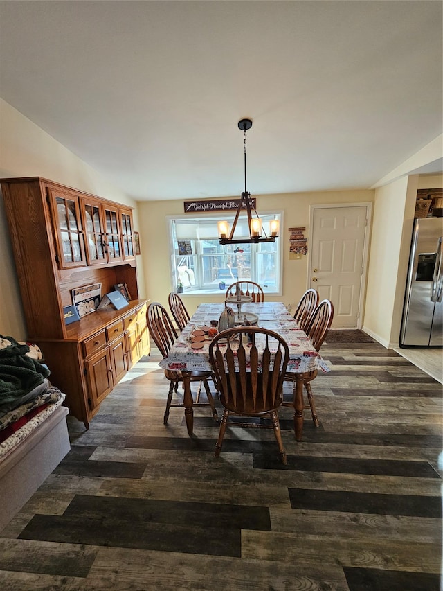 dining space with vaulted ceiling, dark hardwood / wood-style flooring, and an inviting chandelier