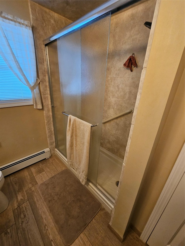 bathroom with toilet, a shower with shower door, and a baseboard radiator