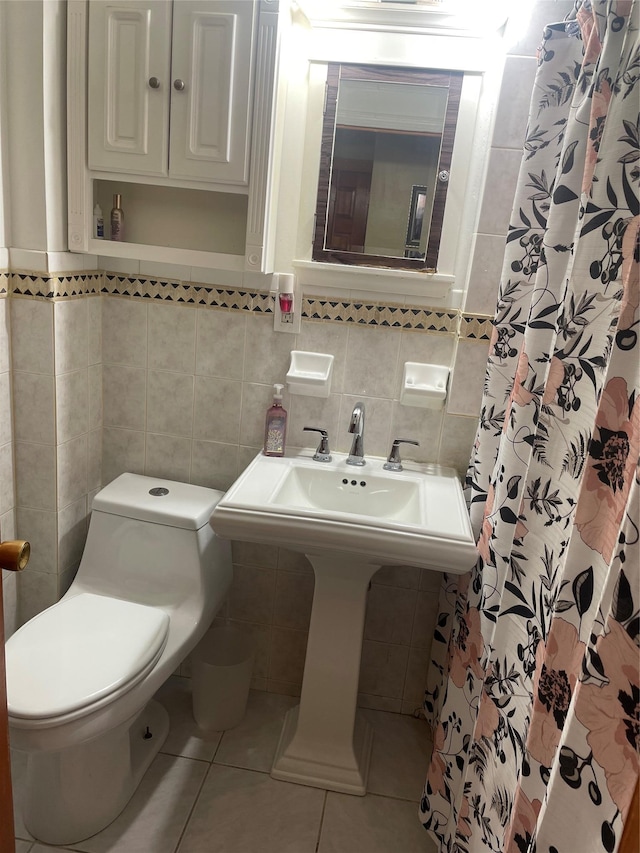 bathroom with tile patterned floors, sink, toilet, tile walls, and curtained shower