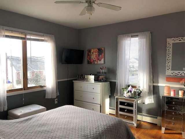 bedroom featuring baseboard heating, ceiling fan, and hardwood / wood-style floors