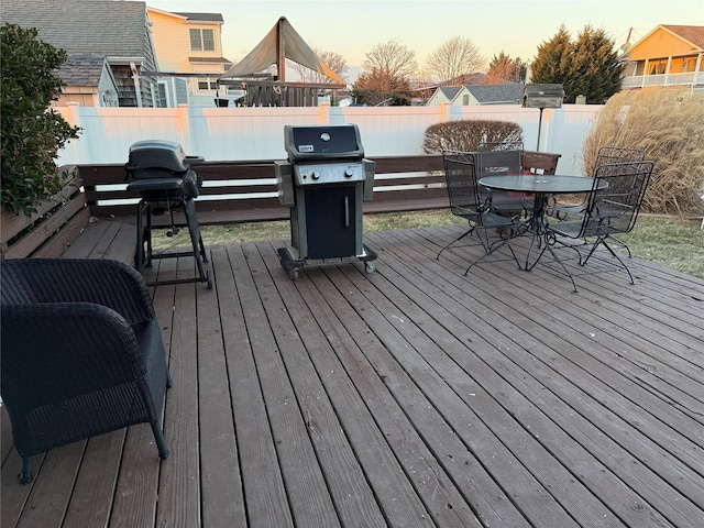 deck at dusk featuring a grill