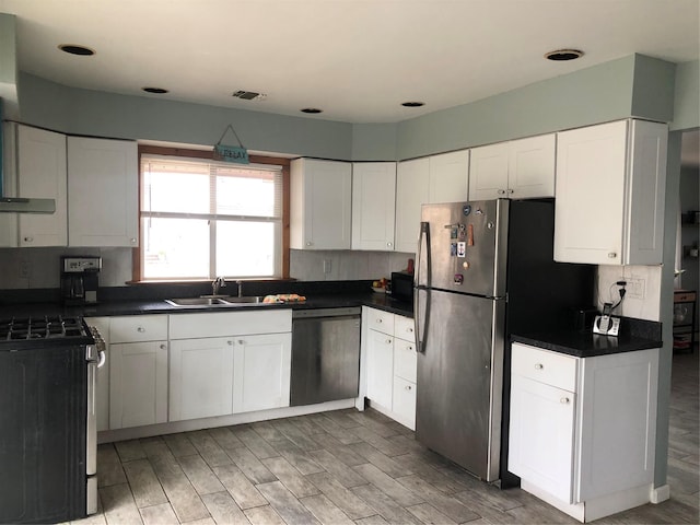 kitchen with sink, white cabinetry, hardwood / wood-style floors, stainless steel appliances, and range hood