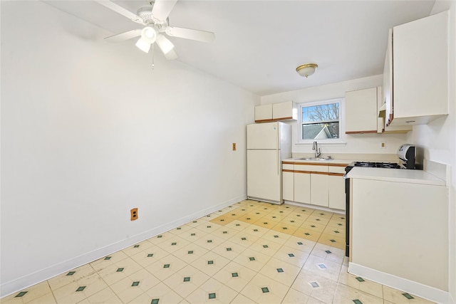 kitchen with stove, white cabinets, white refrigerator, sink, and ceiling fan