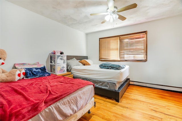 bedroom with a baseboard radiator, ceiling fan, and hardwood / wood-style flooring