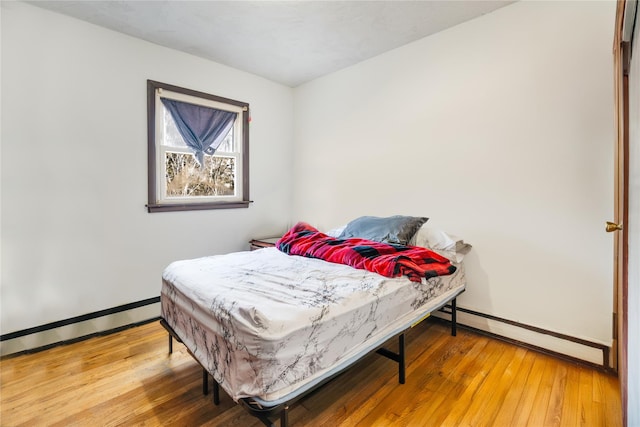 bedroom with hardwood / wood-style floors and a baseboard heating unit