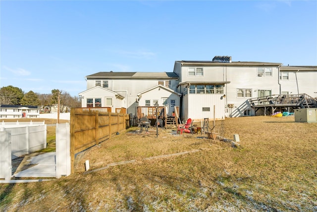 back of property featuring a lawn and a deck