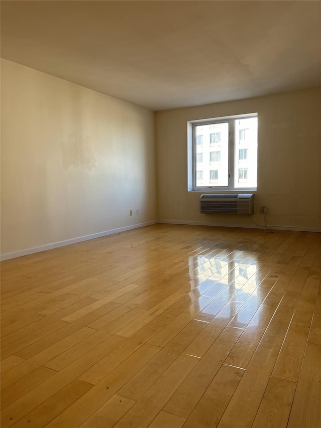 empty room with a wall mounted air conditioner and light hardwood / wood-style floors