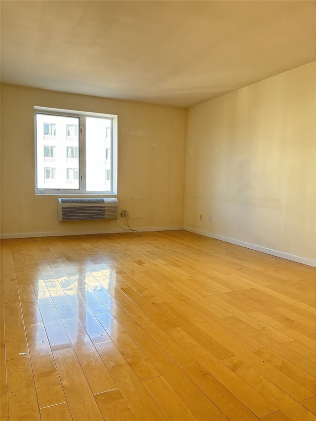 unfurnished room featuring a wall mounted AC and light wood-type flooring