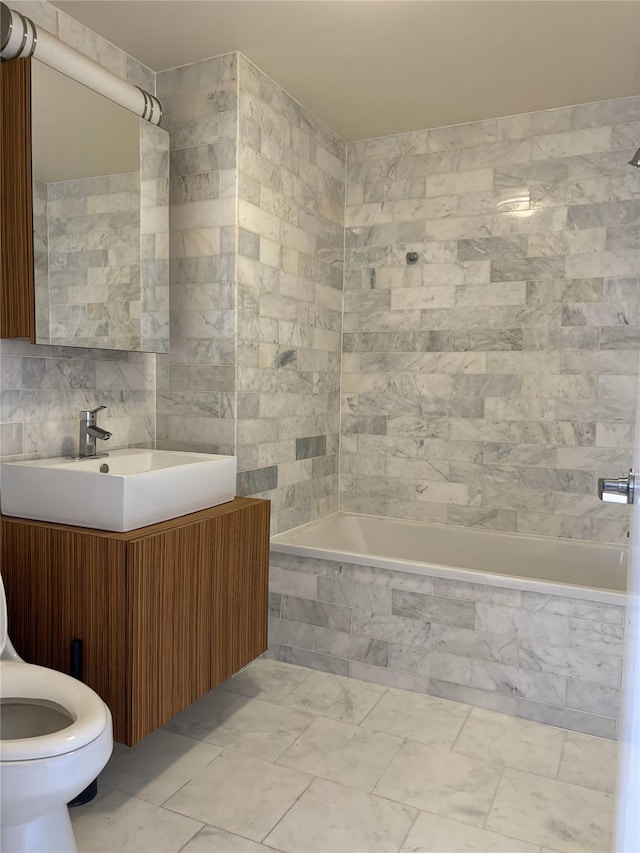 full bathroom with vanity, tile walls, tile patterned flooring, toilet, and tiled shower / bath