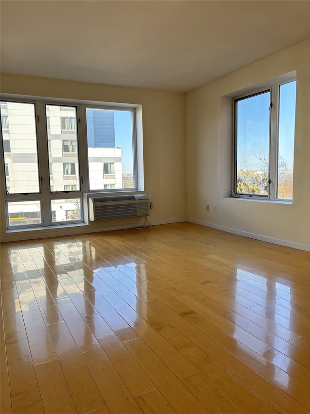 spare room featuring light hardwood / wood-style floors and a wall unit AC