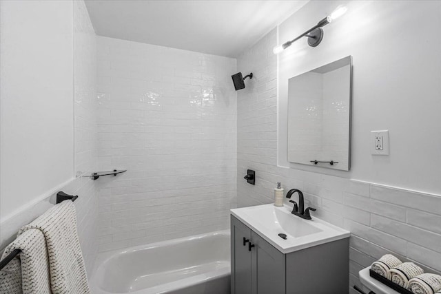 full bathroom featuring vanity, toilet, tile walls, and tiled shower / bath