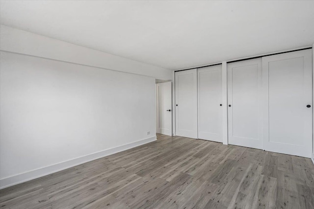 unfurnished bedroom with two closets and light hardwood / wood-style floors