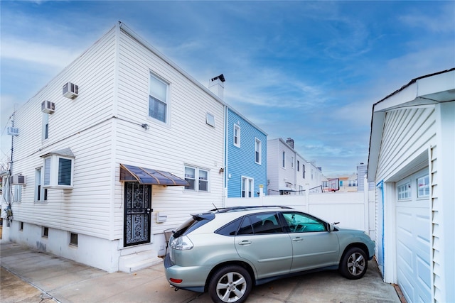 view of side of home with a garage and an AC wall unit