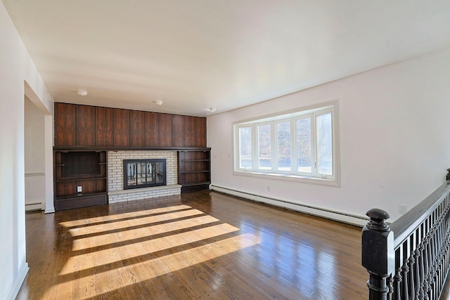 unfurnished living room featuring hardwood / wood-style flooring, a brick fireplace, and a baseboard heating unit