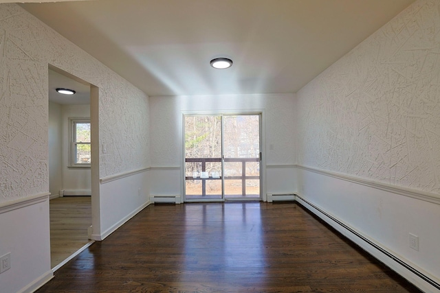 empty room featuring dark hardwood / wood-style flooring and a baseboard heating unit