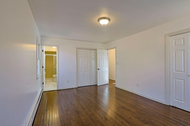 unfurnished bedroom with baseboard heating, ensuite bathroom, and dark hardwood / wood-style floors