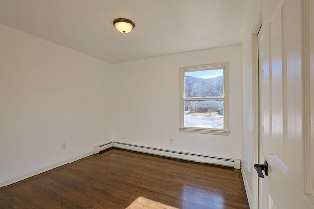 spare room with dark hardwood / wood-style flooring and a baseboard heating unit