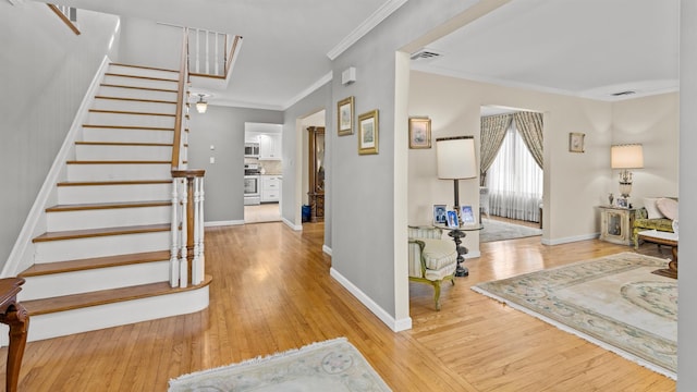 foyer entrance featuring ornamental molding and light wood-type flooring