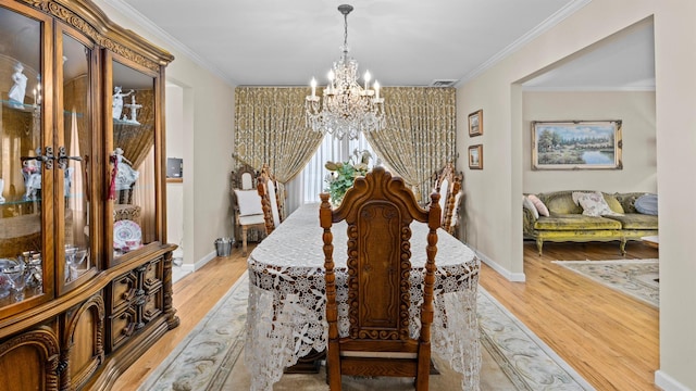 dining area with a chandelier, light hardwood / wood-style floors, and ornamental molding