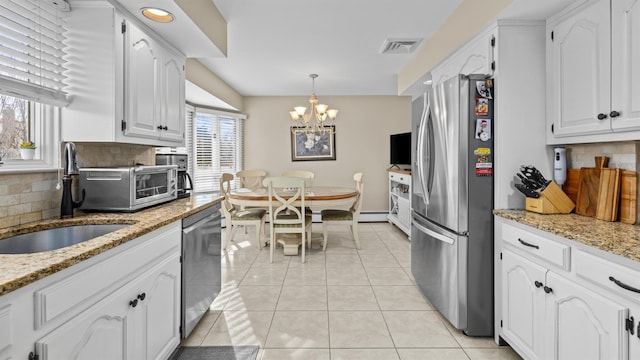 kitchen featuring light stone countertops, stainless steel appliances, pendant lighting, white cabinets, and light tile patterned flooring