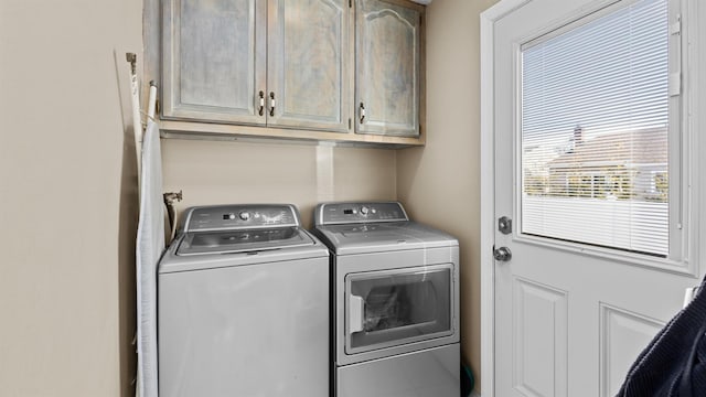 clothes washing area with cabinets and washer and dryer