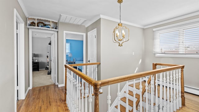 hallway featuring light hardwood / wood-style floors, plenty of natural light, a chandelier, and ornamental molding