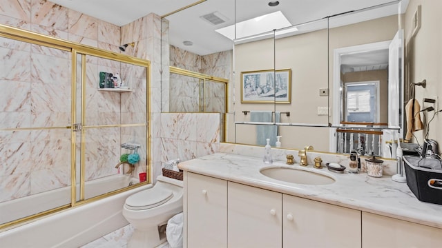 full bathroom featuring vanity, a skylight, toilet, and enclosed tub / shower combo