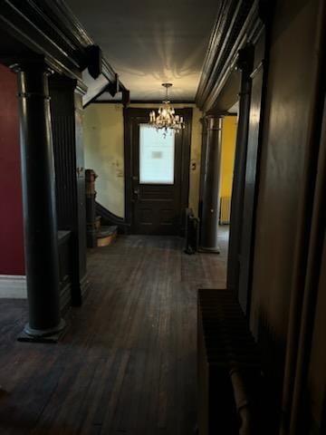 hallway featuring dark hardwood / wood-style floors, radiator, ornamental molding, and an inviting chandelier