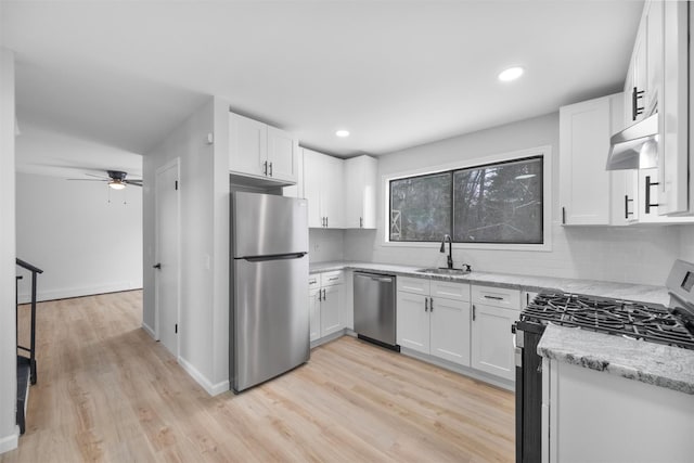 kitchen with white cabinetry, sink, ceiling fan, light stone countertops, and appliances with stainless steel finishes