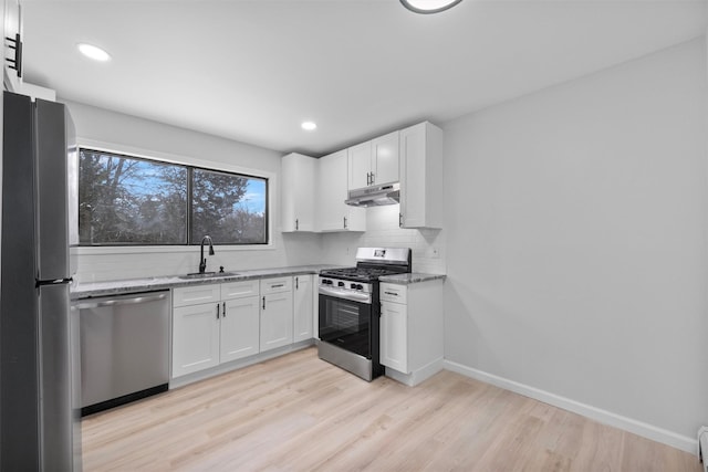 kitchen featuring white cabinets, stainless steel appliances, light stone countertops, and sink