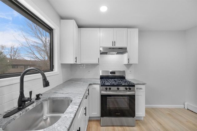 kitchen with light stone counters, baseboard heating, sink, white cabinetry, and stainless steel range with gas stovetop