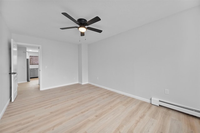 spare room featuring ceiling fan, light hardwood / wood-style flooring, and a baseboard heating unit