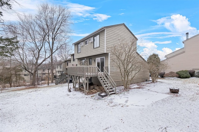 snow covered back of property featuring a deck