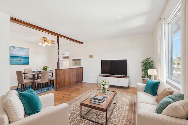 living room with light wood-type flooring, ceiling fan, beam ceiling, and plenty of natural light