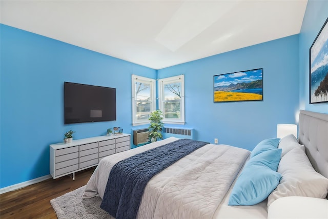 bedroom with dark hardwood / wood-style floors and radiator heating unit