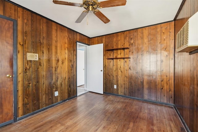 unfurnished room with ceiling fan, crown molding, dark hardwood / wood-style floors, and wooden walls