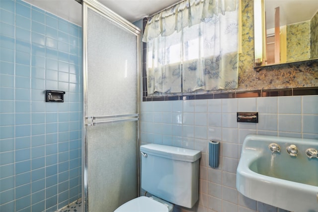 bathroom with toilet, tile walls, a shower with shower door, and sink