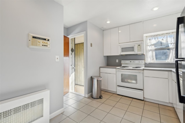 kitchen with light tile patterned floors, white appliances, radiator heating unit, and white cabinets