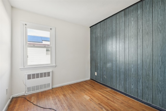 unfurnished room featuring radiator heating unit and light hardwood / wood-style floors