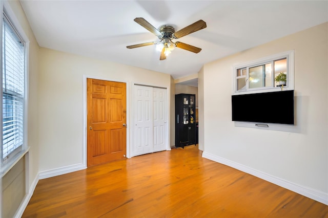 empty room with ceiling fan, a wealth of natural light, and hardwood / wood-style flooring