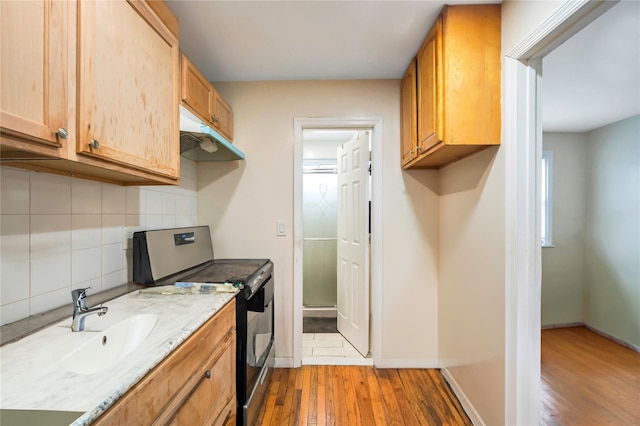 kitchen with range with electric stovetop, backsplash, wood-type flooring, light stone countertops, and sink