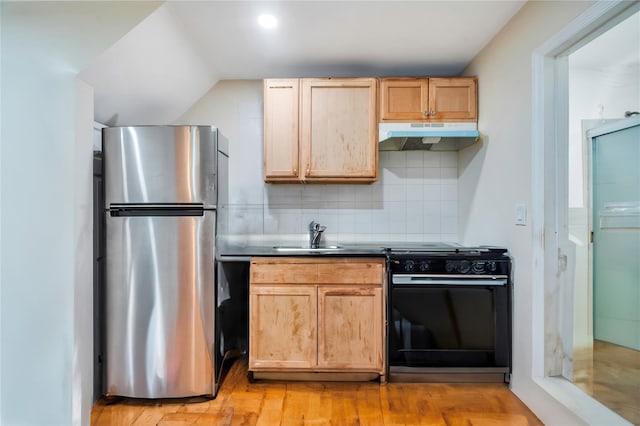 kitchen with stainless steel fridge, black gas range oven, backsplash, light brown cabinetry, and sink