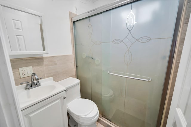 bathroom featuring tasteful backsplash, vanity, tile walls, toilet, and a shower with door