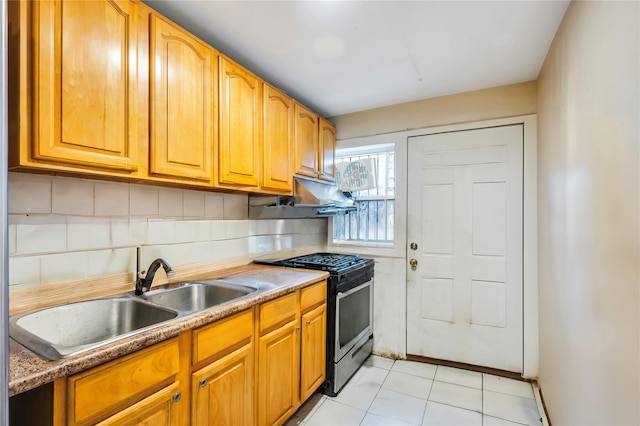 kitchen featuring stainless steel gas range, light tile patterned flooring, decorative backsplash, and sink