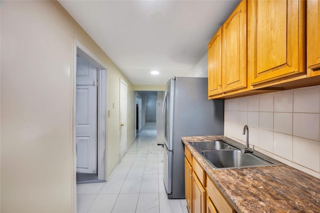 kitchen featuring decorative backsplash, sink, and stainless steel refrigerator